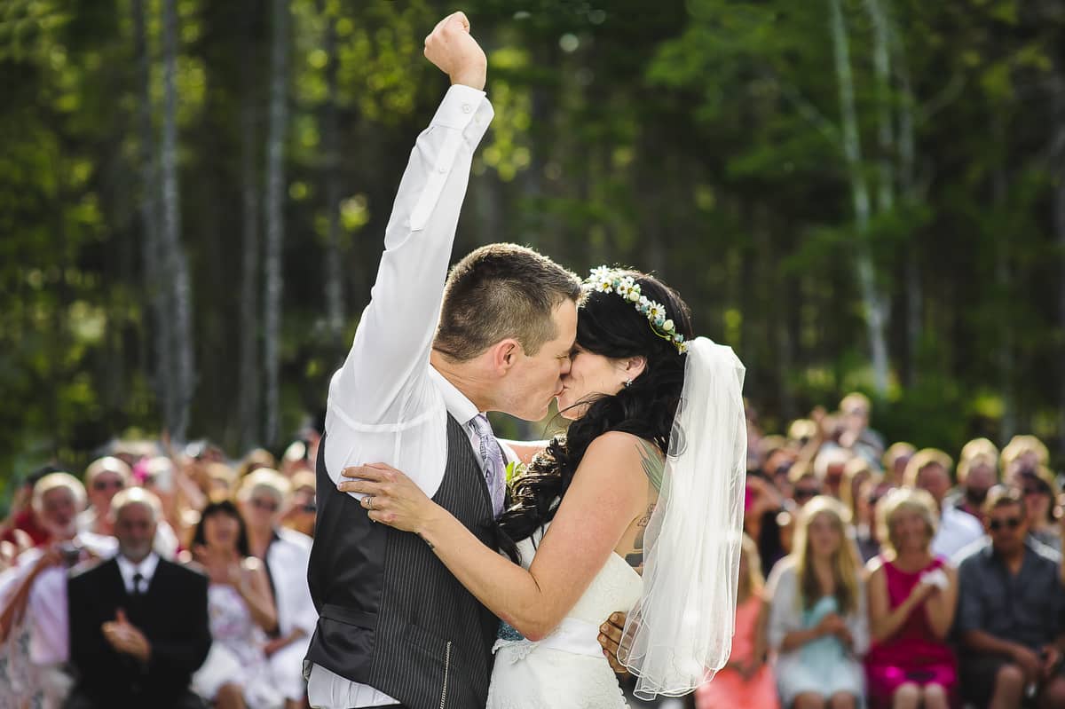 bride and groom kissing while groom fist pumps